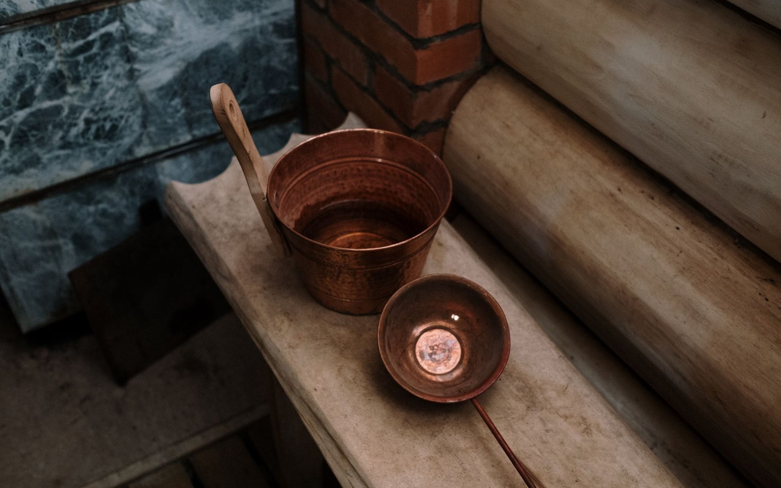 A well-used copper saucepan photographed overhead on a dark iron surface