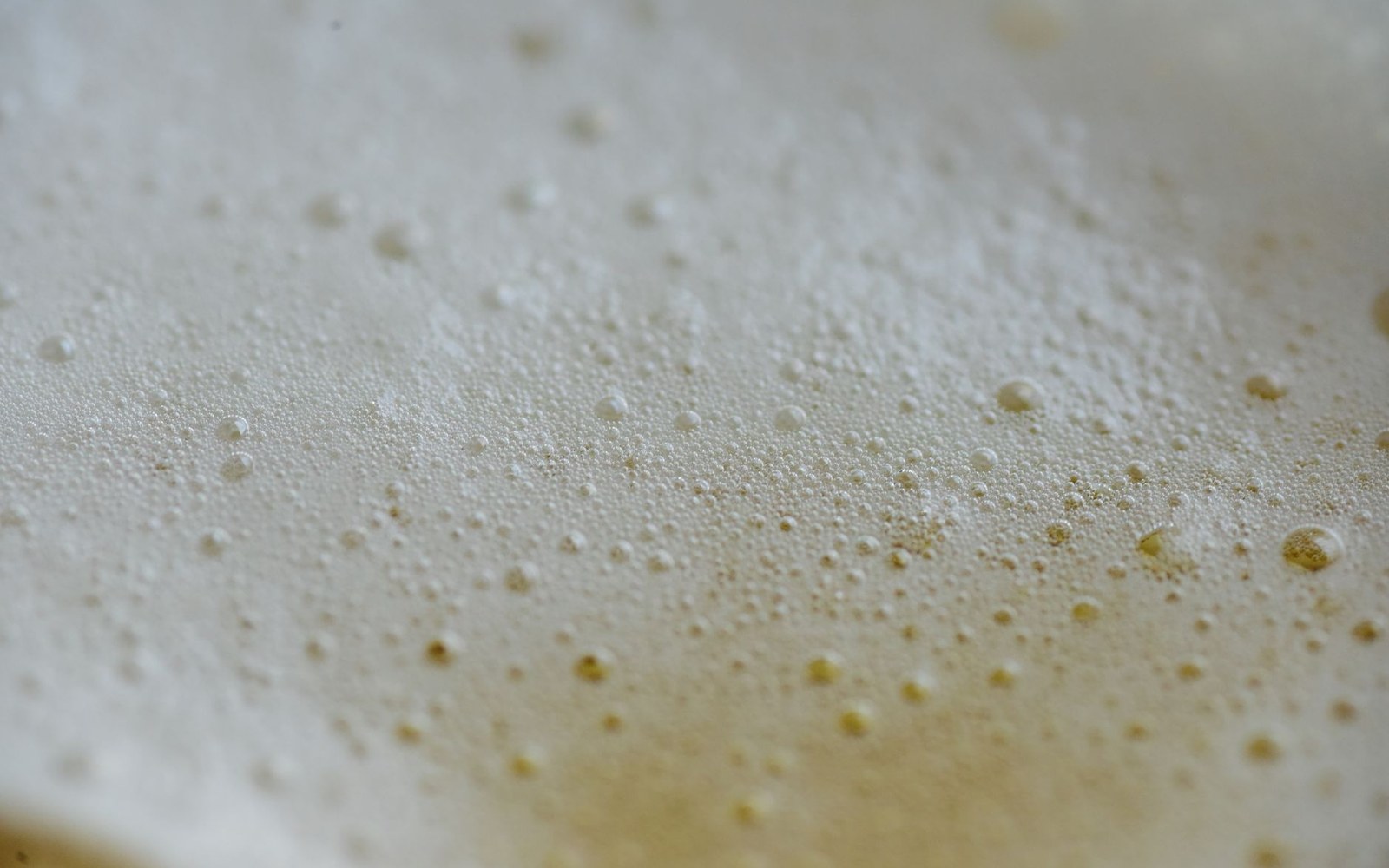 A pale stock in a wide pot showing a single lazy trembling bubble at the surface