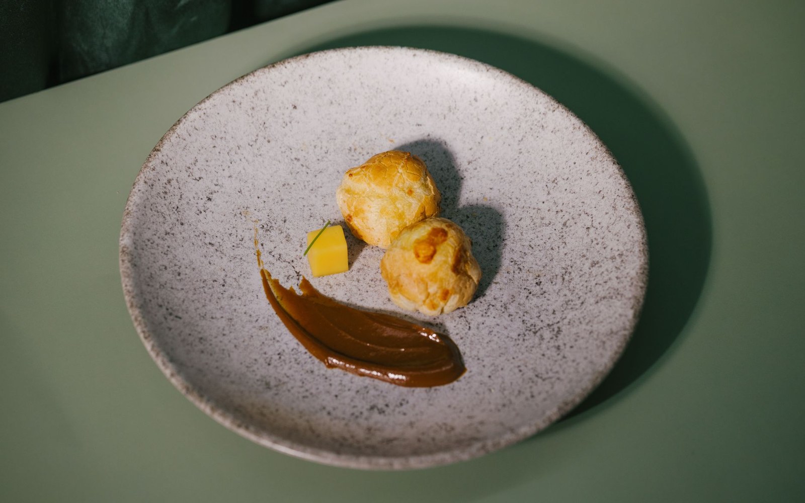 A white plate with a smear of dark sauce across it and a folded cloth beside it on a kitchen surface